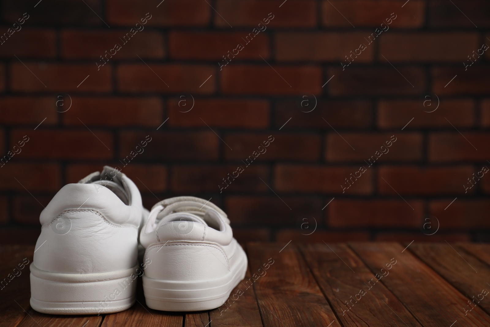 Photo of Big and small sneakers on wooden surface, space for text