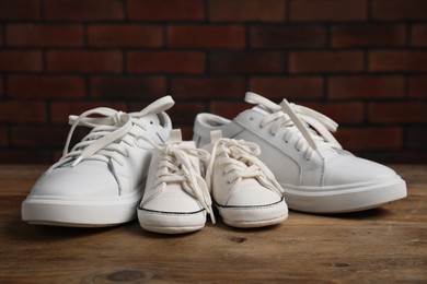 Photo of Big and small sneakers on wooden surface