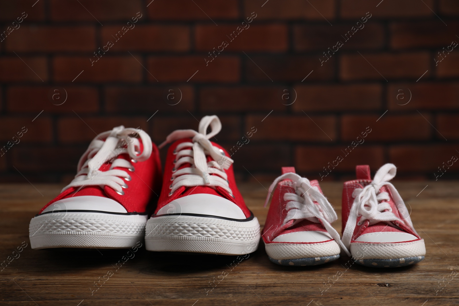 Photo of Big and small sneakers on wooden surface