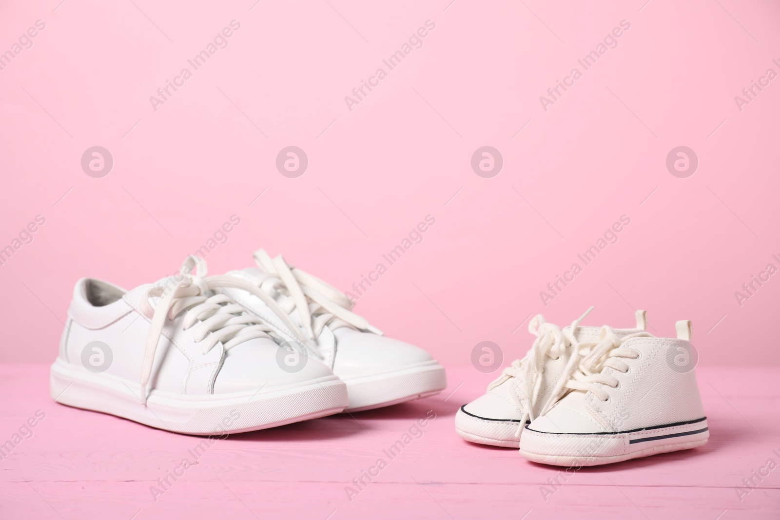 Photo of Big and small sneakers on pink background