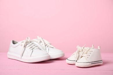 Photo of Big and small sneakers on pink background