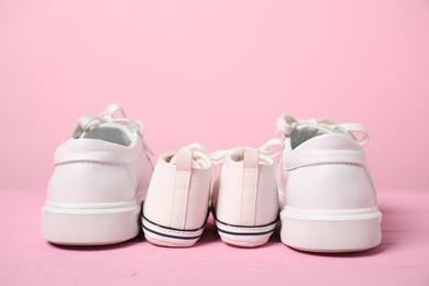 Photo of Big and small sneakers on pink background