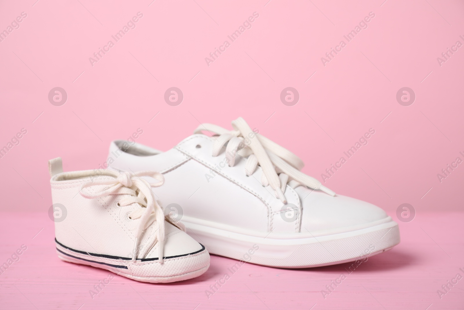 Photo of Big and small sneakers on pink background