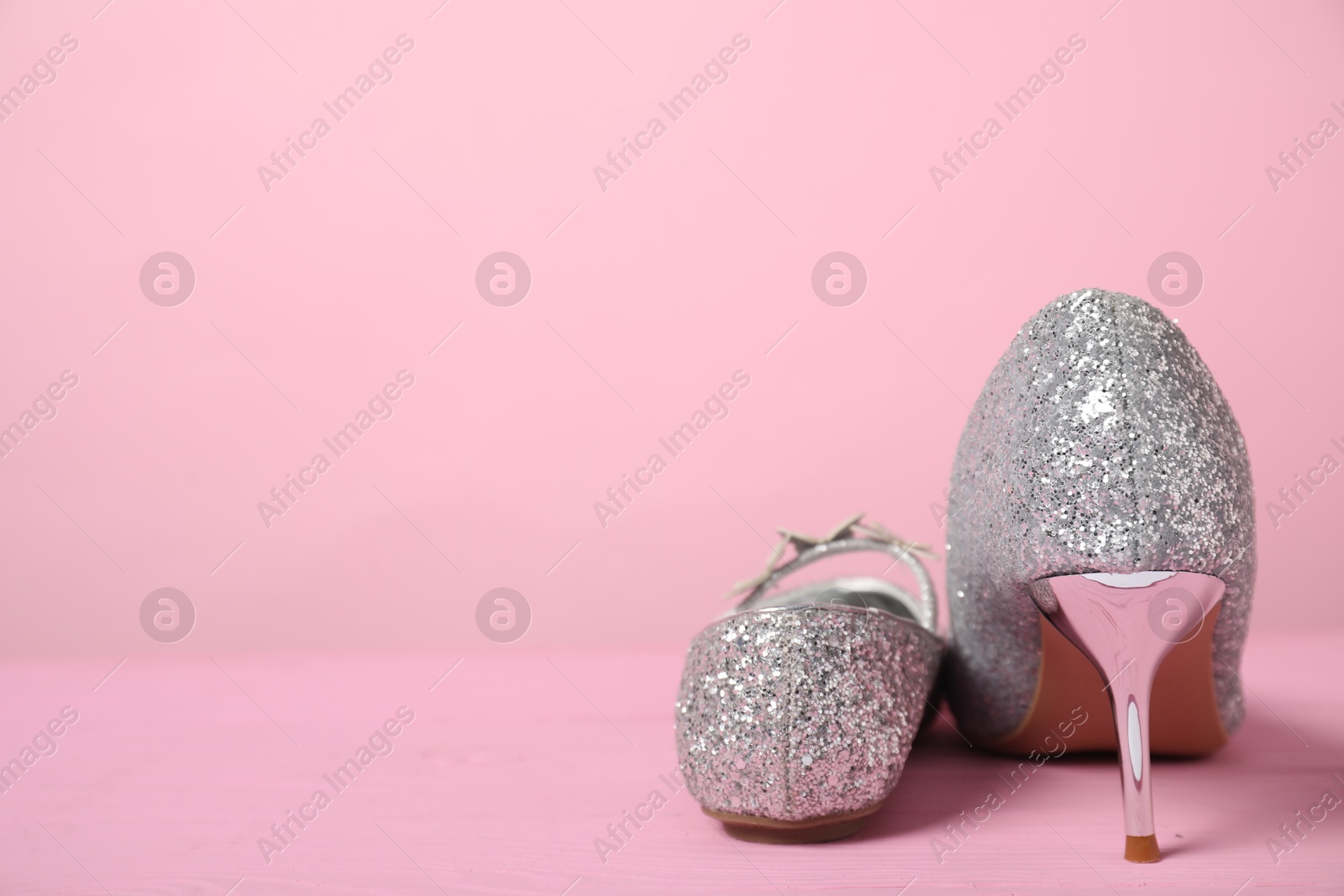 Photo of Big and small shoes on pink background. Space for text