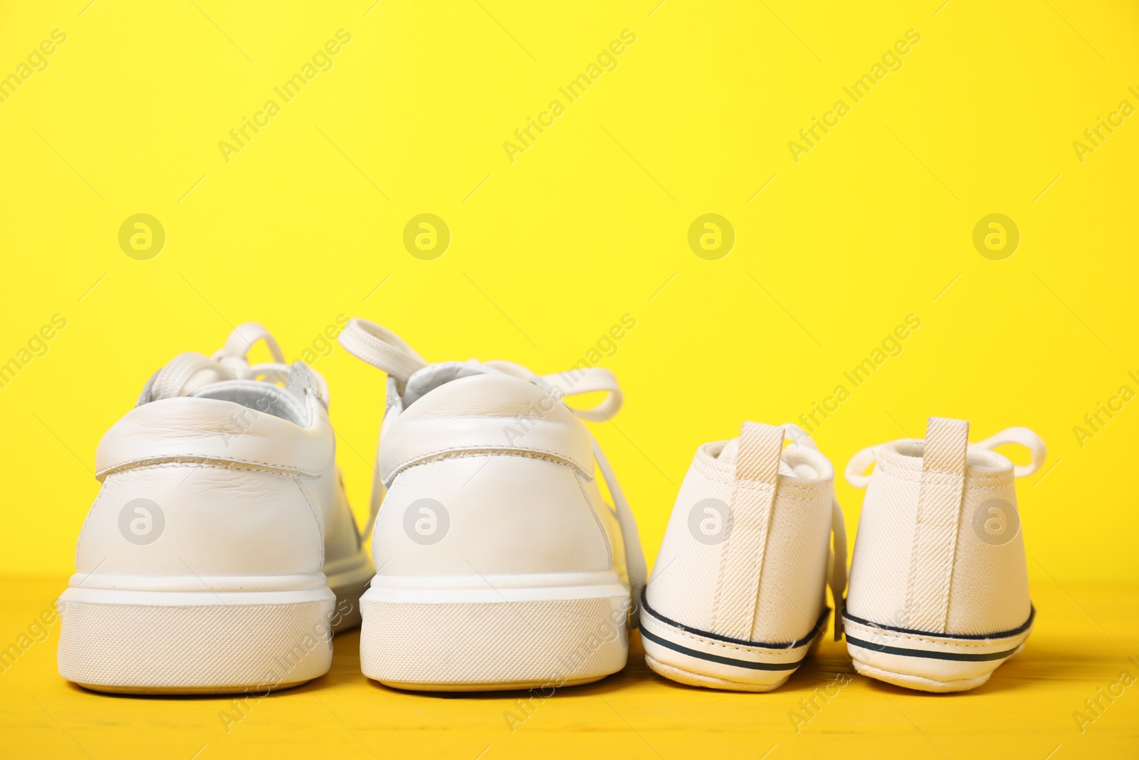 Photo of Big and small sneakers on yellow background