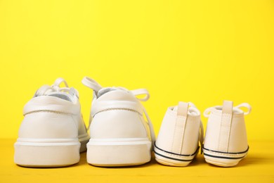 Photo of Big and small sneakers on yellow background