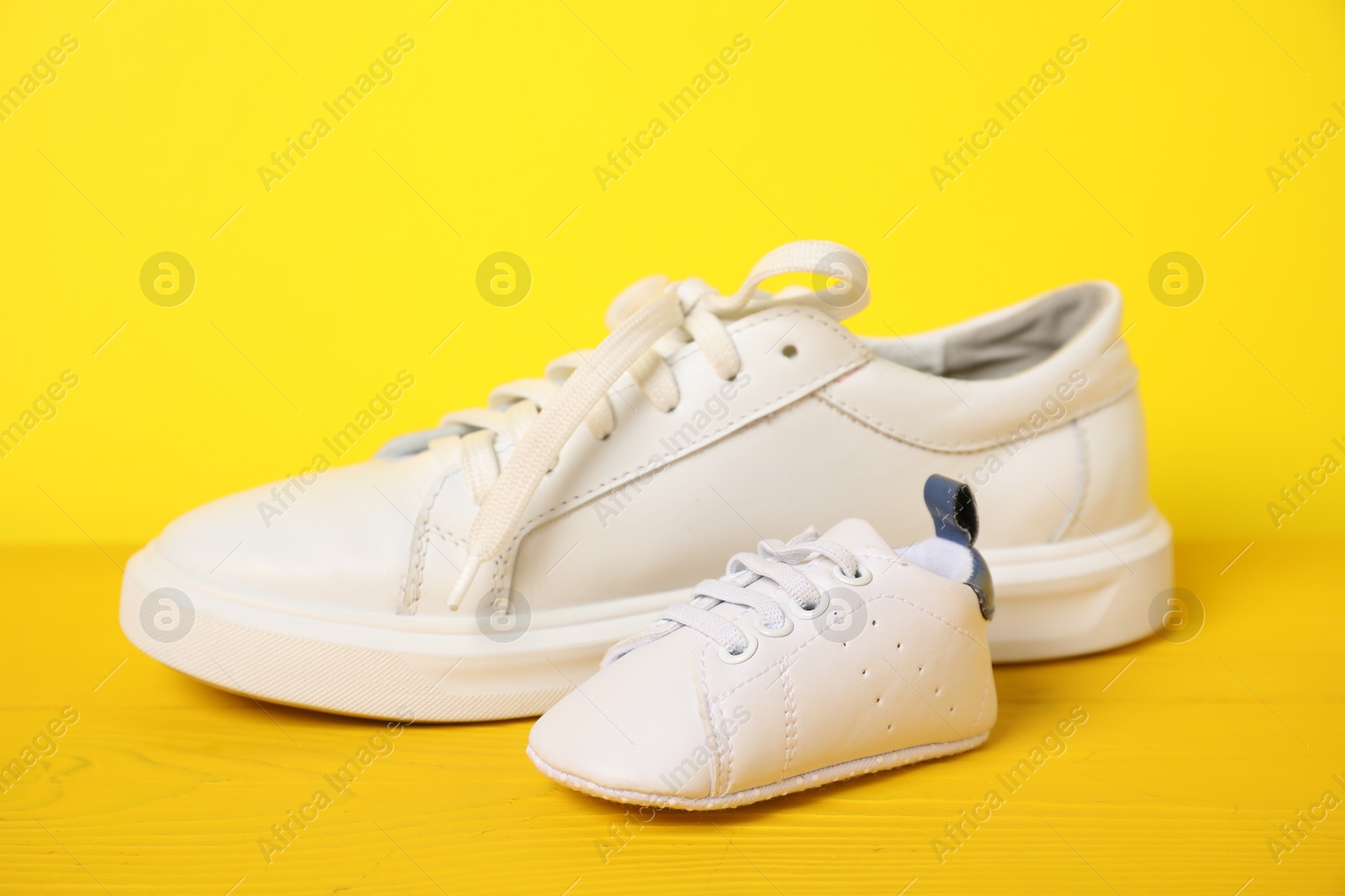 Photo of Big and small sneakers on yellow background