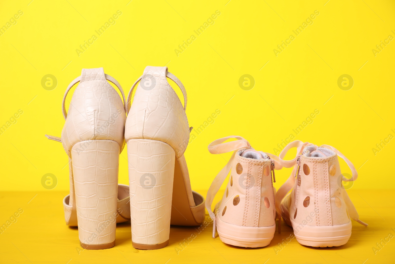 Photo of Big and small shoes on yellow background