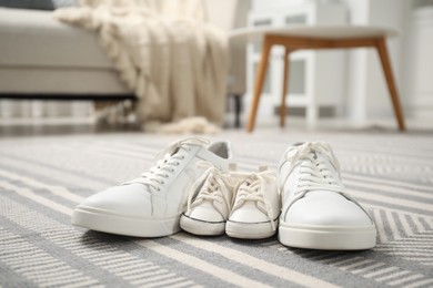 Photo of Big and small sneakers on carpet indoors