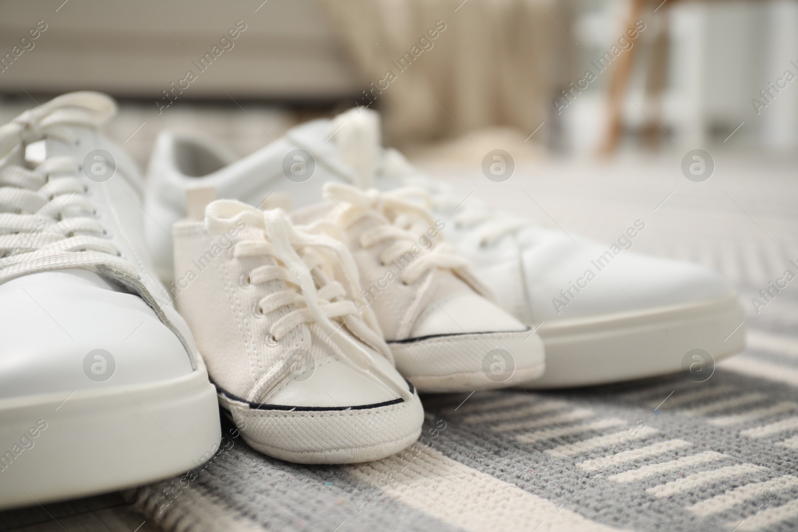 Photo of Big and small sneakers on carpet indoors, closeup