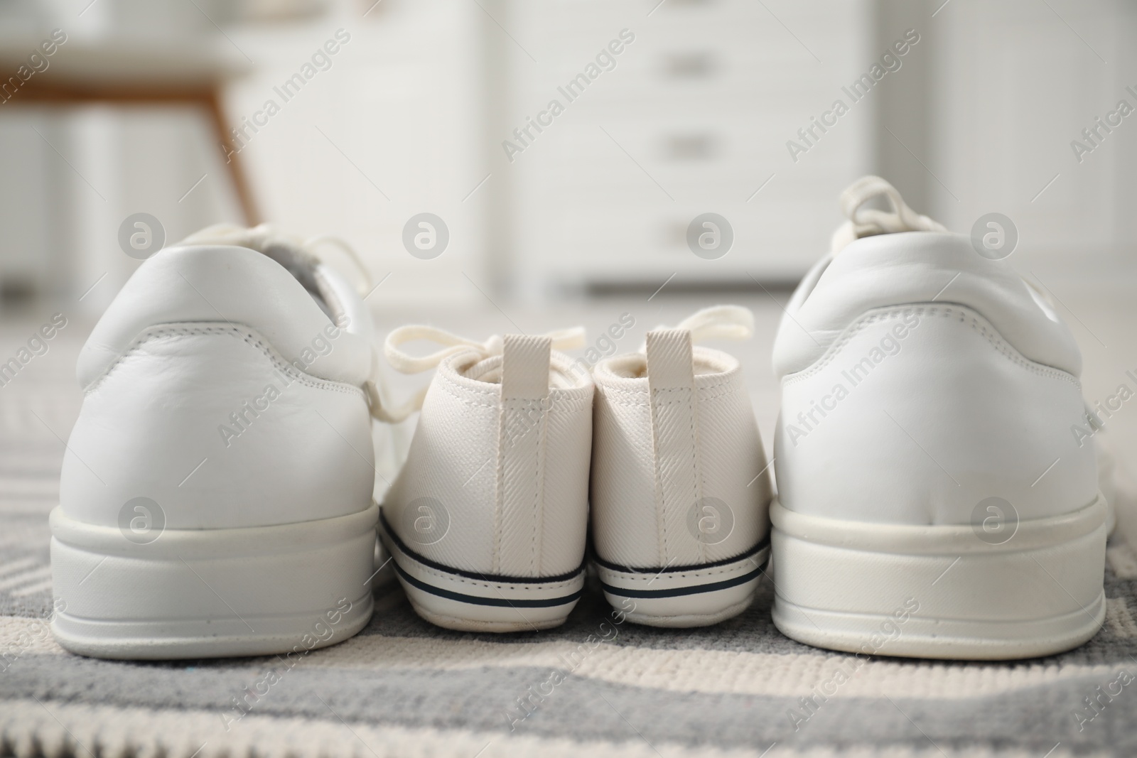 Photo of Big and small sneakers on carpet indoors, closeup