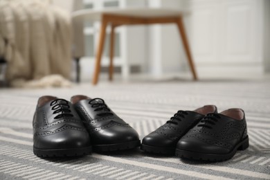 Big and small shoes on carpet indoors