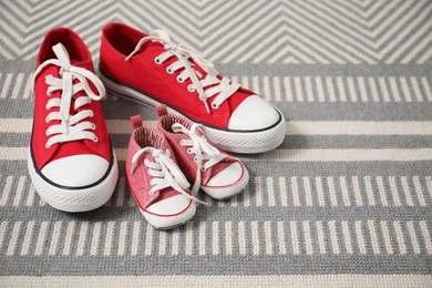 Photo of Big and small sneakers on carpet indoors, space for text