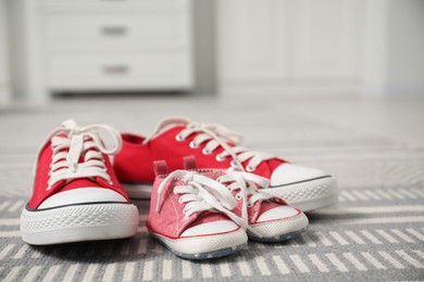 Photo of Big and small sneakers on carpet indoors