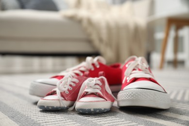 Photo of Big and small sneakers on carpet indoors