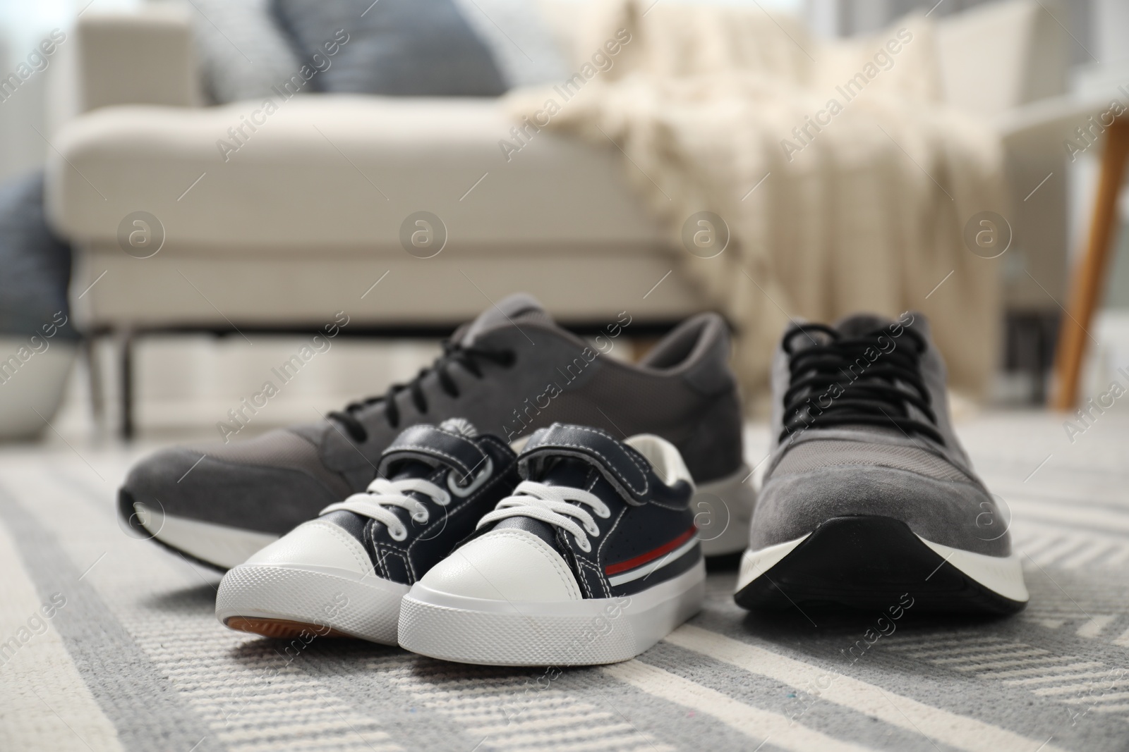 Photo of Big and small sneakers on carpet indoors