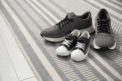 Photo of Big and small sneakers on carpet, space for text