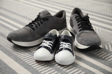 Photo of Big and small sneakers on carpet indoors