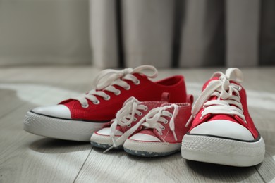 Photo of Big and small sneakers on floor indoors