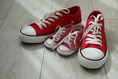 Photo of Big and small sneakers on wooden floor