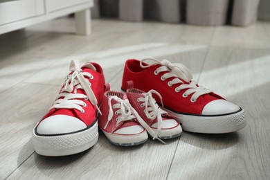 Photo of Big and small sneakers on floor indoors