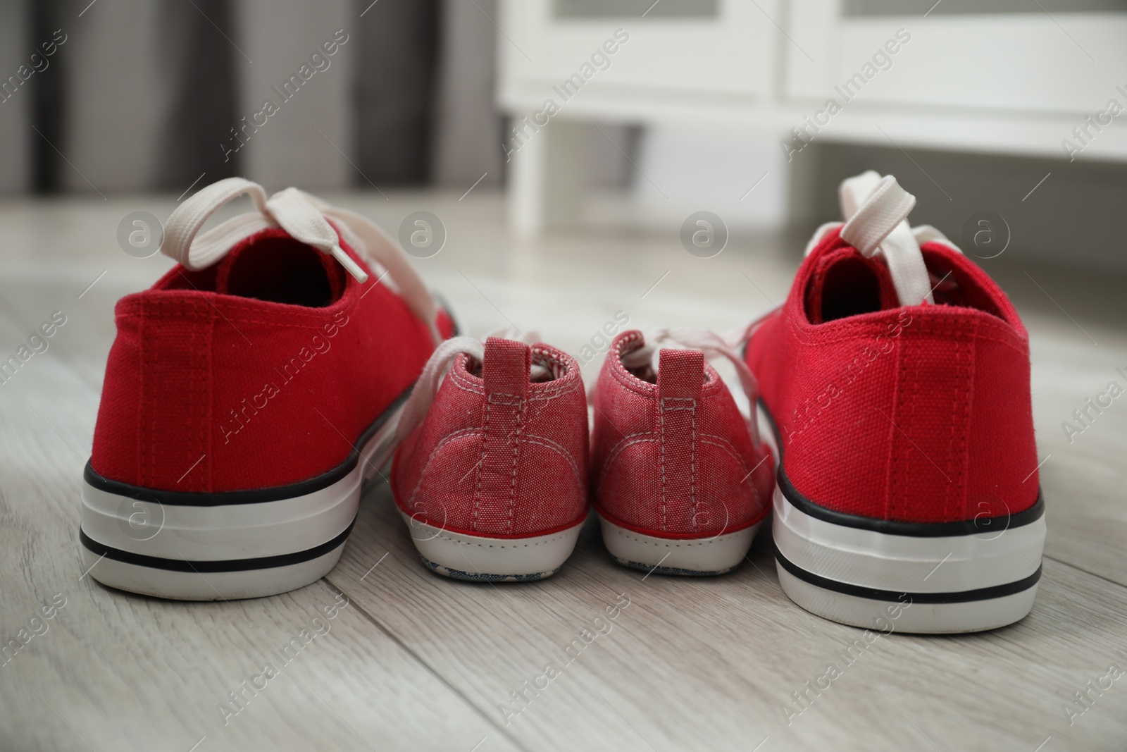 Photo of Big and small sneakers on floor indoors