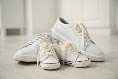 Photo of Big and small sneakers on floor indoors