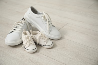 Photo of Big and small sneakers on floor, space for text