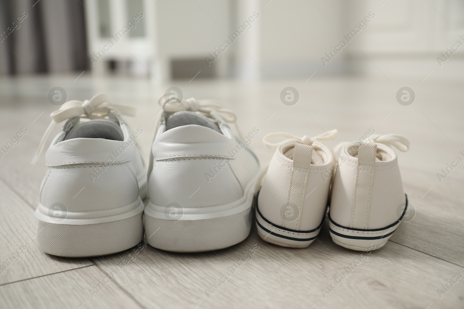 Photo of Big and small sneakers on floor indoors