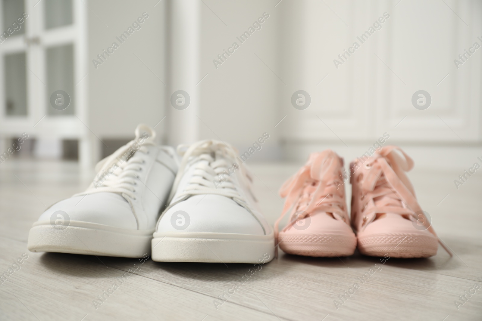 Photo of Big and small sneakers on floor indoors