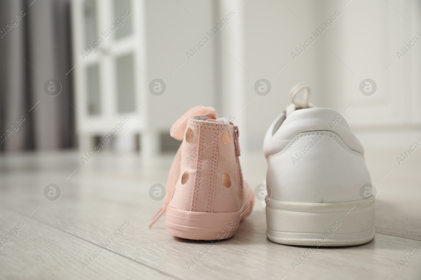 Photo of Big and small sneakers on floor indoors, space for text