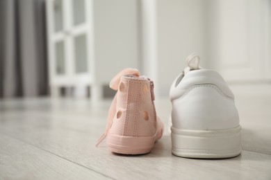 Photo of Big and small sneakers on floor indoors, space for text