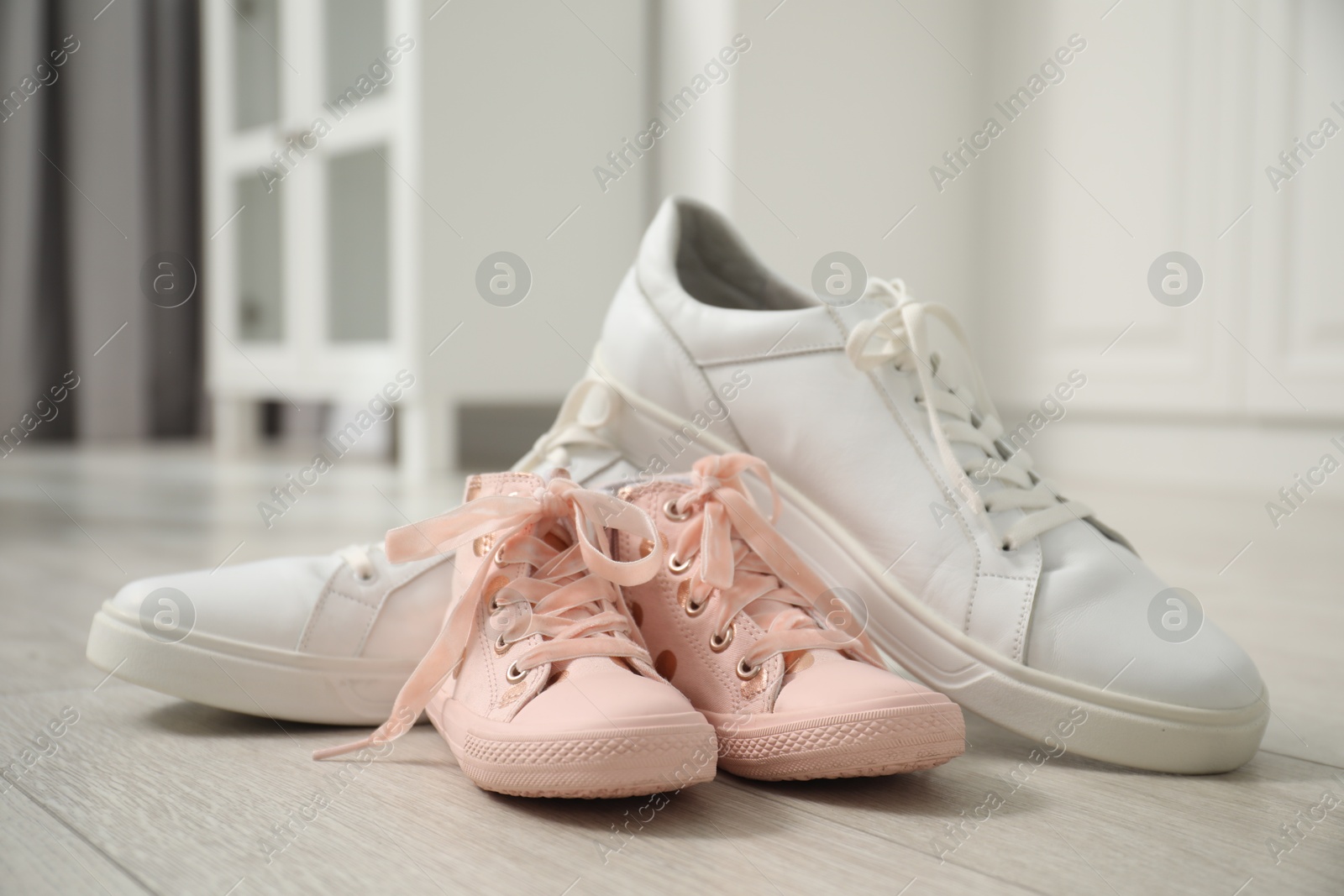 Photo of Big and small sneakers on floor indoors