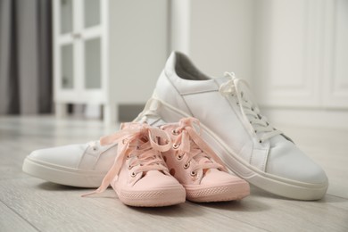 Photo of Big and small sneakers on floor indoors