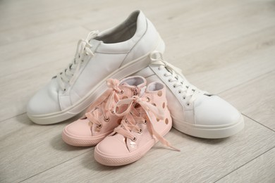 Photo of Big and small sneakers on wooden floor