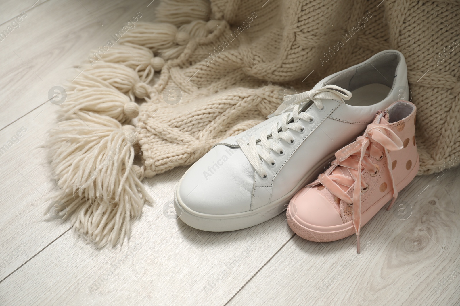 Photo of Big and small sneakers on wooden floor