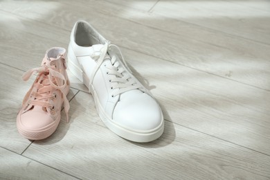 Photo of Big and small sneakers on floor. Space for text