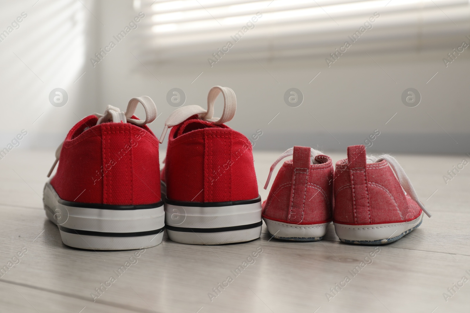 Photo of Big and small sneakers on floor indoors