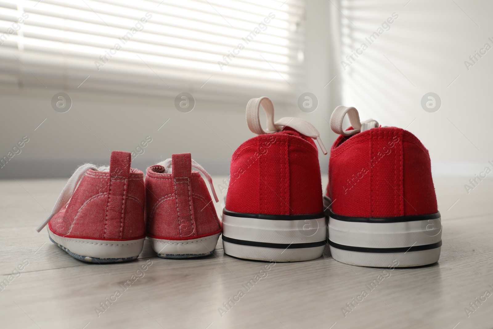 Photo of Big and small sneakers on floor indoors