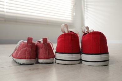 Big and small sneakers on floor indoors