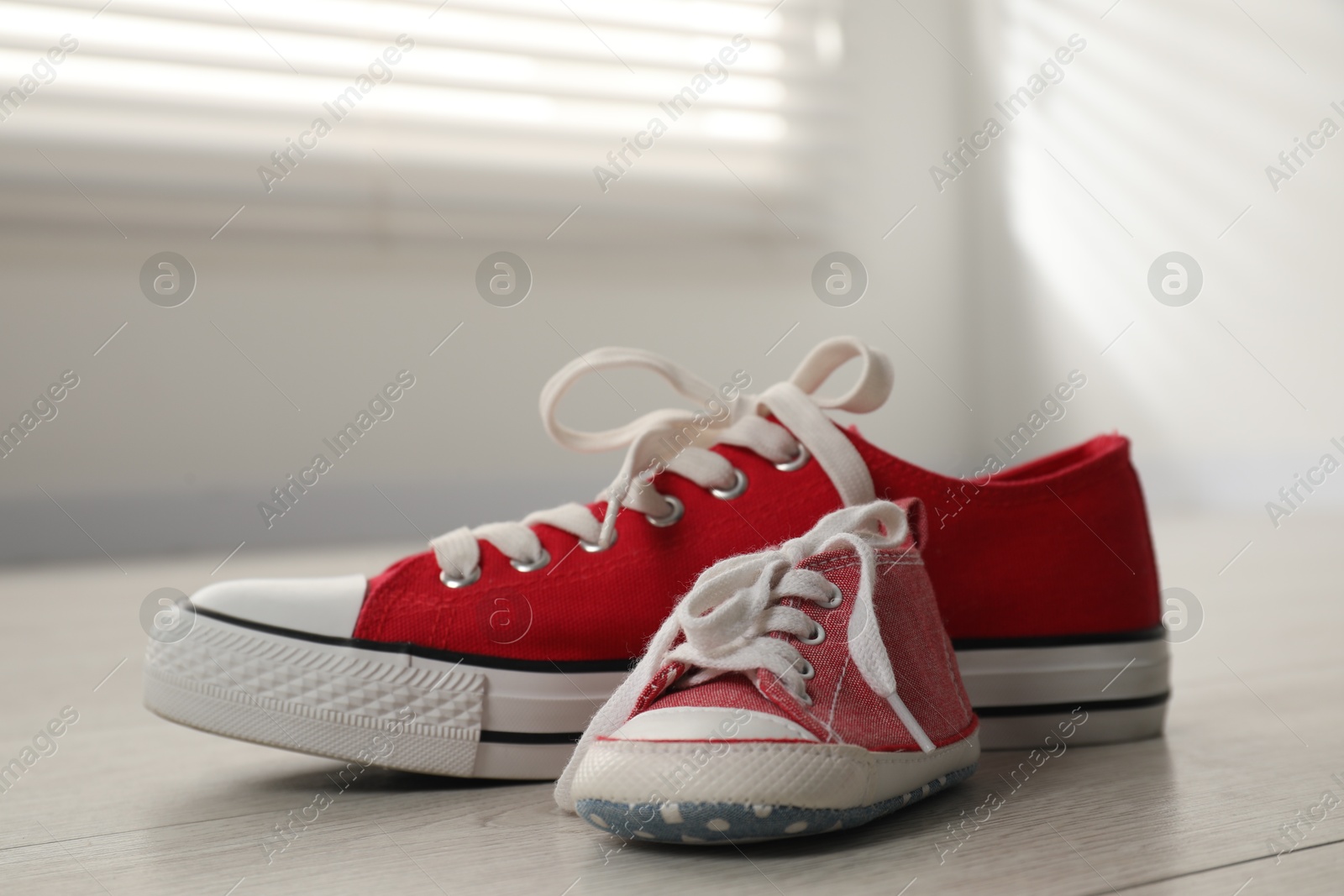 Photo of Big and small sneakers on floor indoors