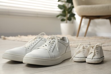 Photo of Big and small sneakers on floor indoors