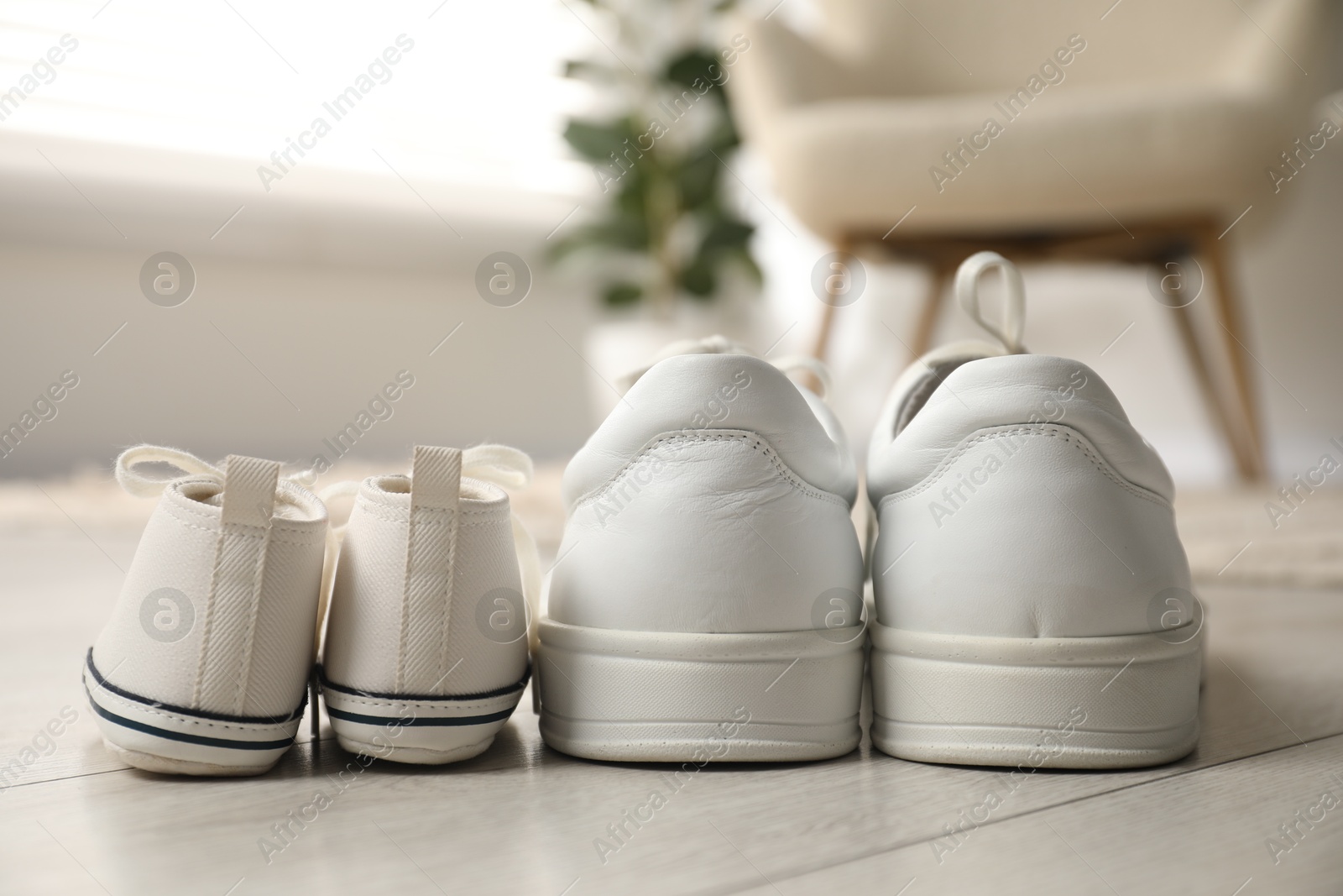 Photo of Big and small sneakers on floor indoors