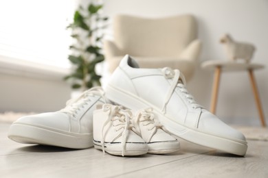 Photo of Big and small sneakers on floor indoors, closeup