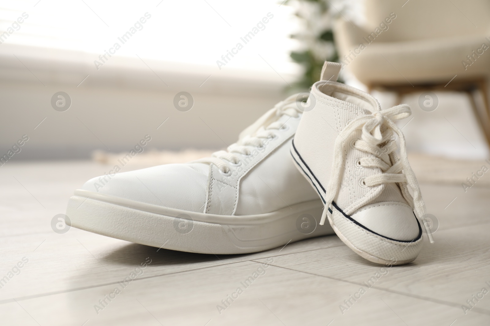 Photo of Big and small sneakers on floor indoors, closeup