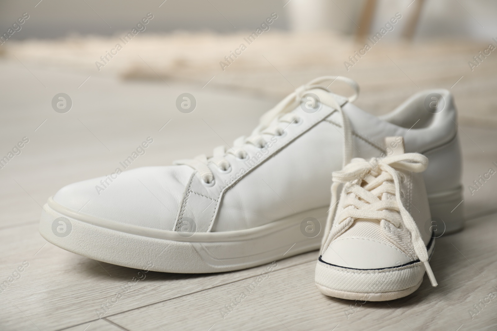 Photo of Big and small sneakers on floor indoors, closeup