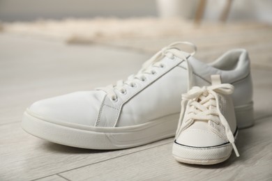 Big and small sneakers on floor indoors, closeup