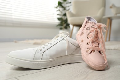 Photo of Big and small sneakers on floor indoors