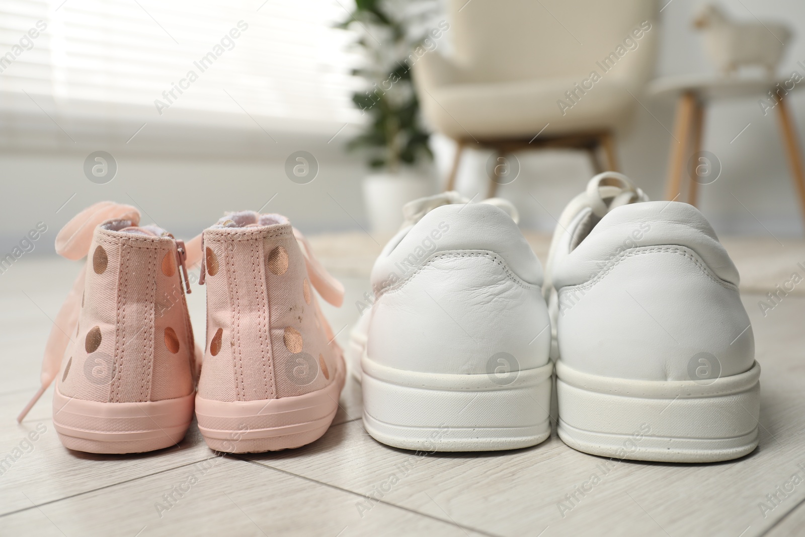 Photo of Big and small sneakers on floor indoors