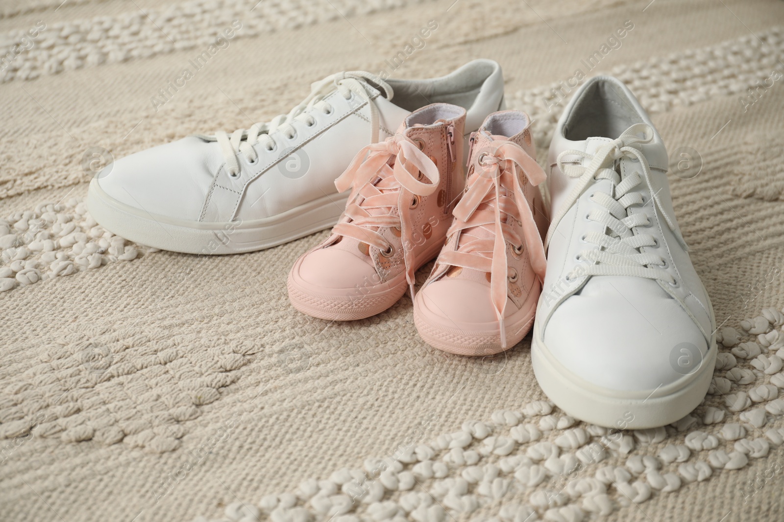 Photo of Big and small sneakers on beige carpet